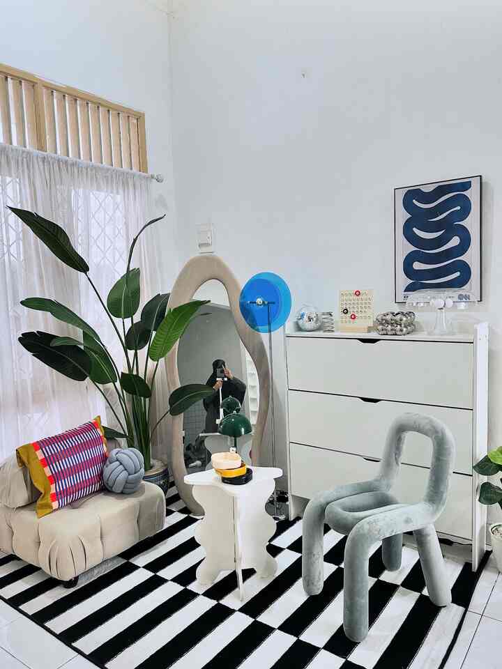 White and gray toned small living room featuring beige sofa, gray velvet chair, curvy mirror, and striped rug in a simple modern style