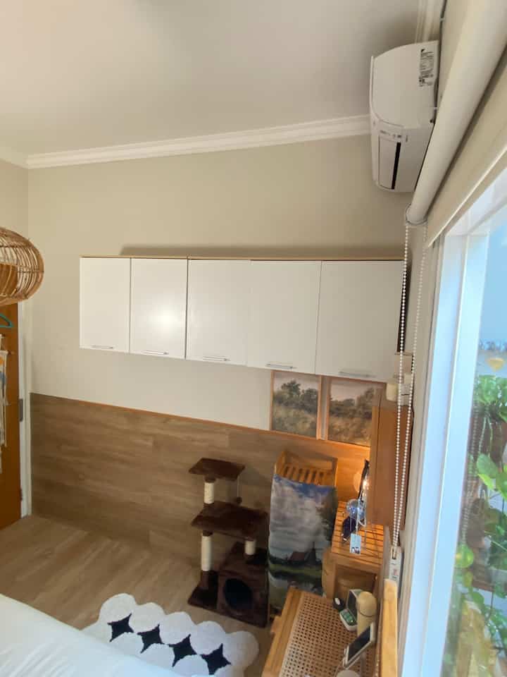Natural color and wood tone small living room featuring a cat tower and white storage cabinets with a cozy atmosphere