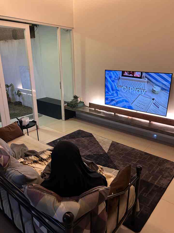 Beige and black toned living room featuring a black metal frame sofa and large flat-screen TV in a modern setting