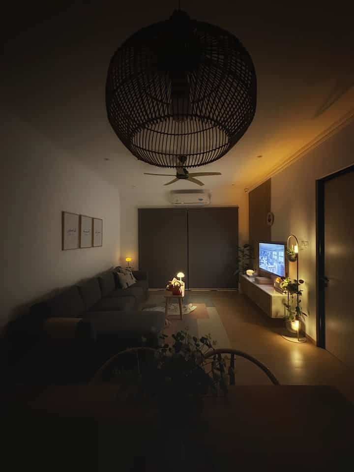 A black, gray, and wood tone open living and dining space featuring a simple modern sofa and mood lighting creating a cozy night vibe.