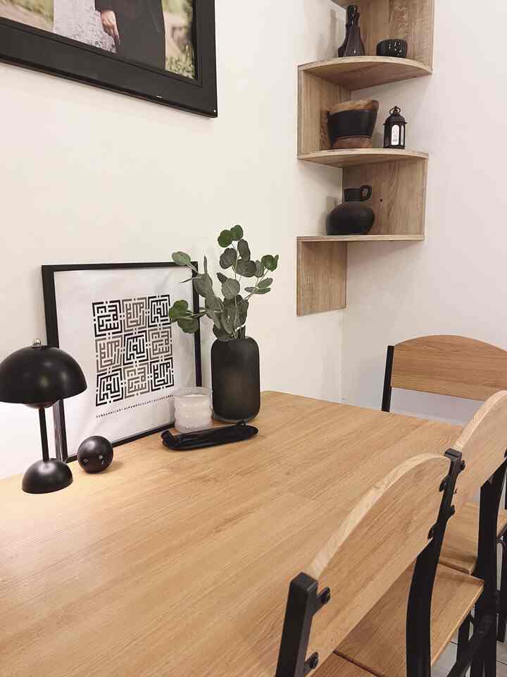 Wood tone dining table and chairs in a neat dining room, featuring wall decor and a candle for a modern atmosphere