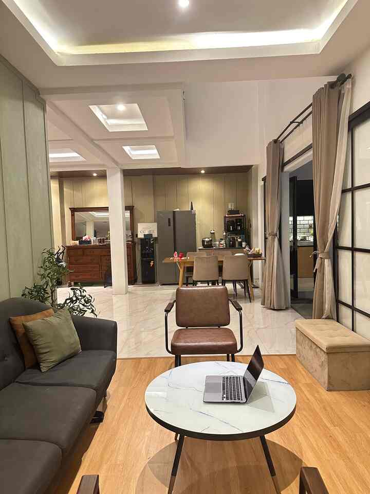 Modern and simple open-plan living room and kitchen space featuring wood tone flooring and beige curtains with warm ambient lighting