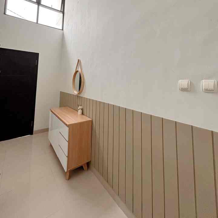 Beige and white toned entrance featuring a wood-toned cabinet and a round mirror with a clean atmosphere