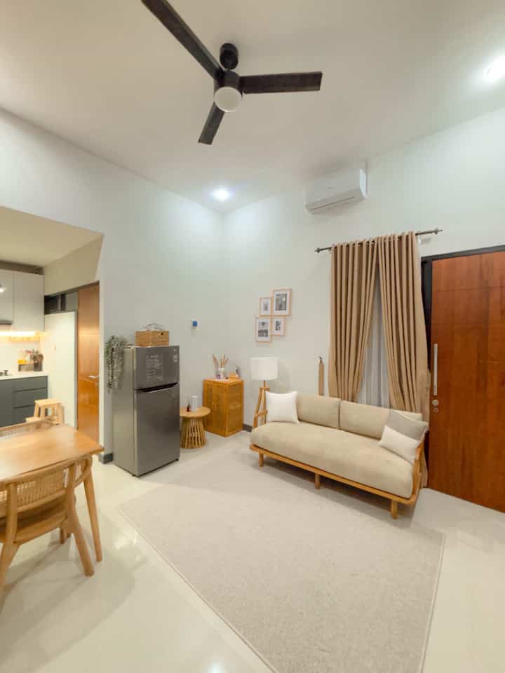 White and brown toned open space living room and kitchen featuring wooden furniture and a clean layout