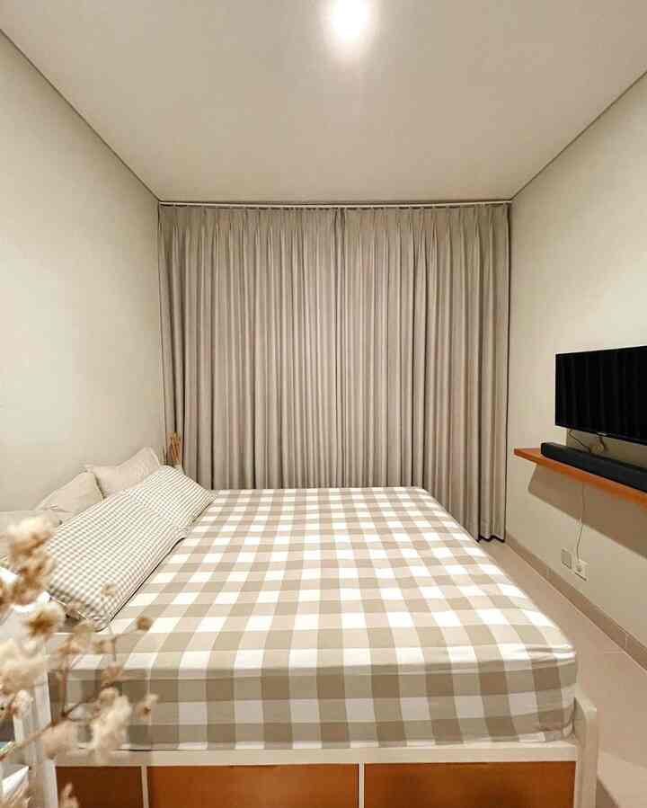 Small bedroom in beige and white tones, featuring a central checkered bed and blackout curtains in a modern setting