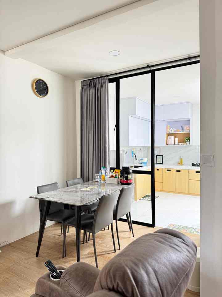 A modern dining room and open kitchen in white and wood tones, featuring a sleek dining table and chairs with clean design