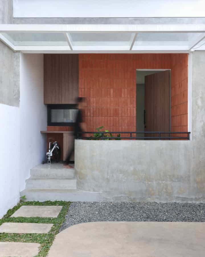Brown wood tones and concrete finish entrance facade featuring storage cabinet, with a natural and modern atmosphere
