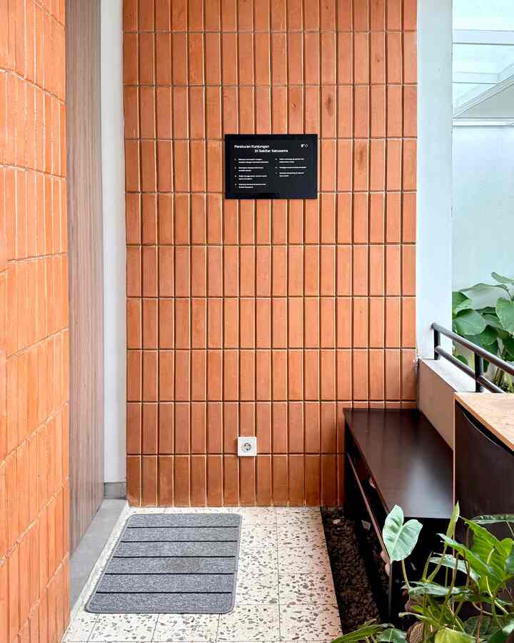 Narrow entrance space with warm brown brick walls and a shoe cabinet