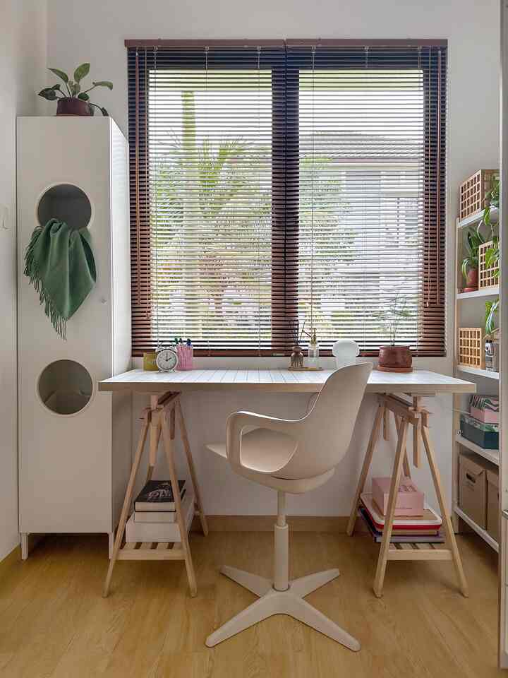 Natural wood tone and white compact home office featuring a clean desk, swivel chair, and organized storage with warm atmosphere