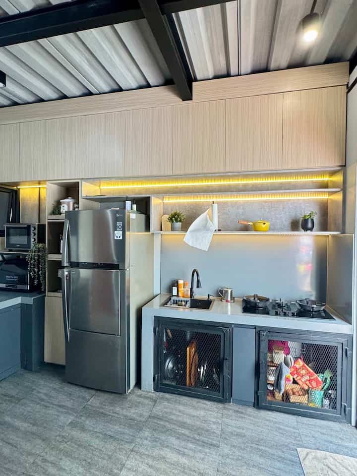 Proses Renovasi Dapur: Dari Tidak Proper ke Dream Kitchen

Dapur lama kami adalah bawaan developer, dan terus terang, jauh dari kata ideal. Ketinggiannya tidak proporsional, sehingga sering kali menyulitkan saya saat memasak. Ditambah lagi, desainnya yang standar dan material yang kurang memadai membuat dapur terasa tidak nyaman dan kurang fungsional.

Melihat kondisi ini, saya dan keluarga memutuskan untuk merenovasi total dapur agar lebih sesuai dengan kebutuhan kami. Proyek ini menjadi perjalanan panjang, tetapi hasil akhirnya sangat memuaskan—dapur impian kami kini terwujud!

Proses Renovasi
	1.	Desain dan Material yang Fungsional
Kami memilih kabinet full sampai ke atap untuk memaksimalkan ruang penyimpanan. Kabinet ini menggunakan motif kayu yang memberikan kesan hangat dan estetik, dipadukan dengan solid surface abu-abu untuk backsplash dan toptable. Kombinasi ini menciptakan kesan modern dan elegan.
	2.	Perlindungan Terhadap Rayap
Kabinet bawah dibuat dari material PVC agar bebas dari masalah rayap dan lebih tahan lama. Kabinet bawah dirancang khusus untuk menyimpan alat masak, alat makan, serta satu laci khusus untuk bumbu.
	3.	Pemilihan Lantai yang Tepat
Lantai dapur menggunakan granit gelap yang tidak hanya kokoh dan tahan lama tetapi juga memberikan tampilan yang mewah. Selain itu, warna gelap membantu menyamarkan noda, membuat dapur lebih mudah dirawat.

Fasilitas Dapur Impian

Kini, dapur saya dilengkapi dengan berbagai alat masak modern yang membuat aktivitas memasak menjadi lebih praktis dan menyenangkan:
	•	Mesin kopi untuk pagi-pagi yang lebih produktif.
	•	Dish dryer untuk memastikan peralatan makan selalu higienis.
	•	Slow cooker, oven, dan air fryer untuk eksplorasi resep-resep baru.
	•	Kompor tiga tungku yang cukup untuk kebutuhan memasak sehari-hari.

Setiap alat memiliki tempat khusus di kabinet, membuat dapur terlihat rapi sekaligus fungsional.

Hasil Akhir: Dream Kitchen Terwujud

Setelah renovasi, dapur kami benar-benar berubah. Kini, dapur bukan hanya tempat memasak, tetapi juga ruang favorit di rumah. Dengan desain yang cantik dan alat masak yang menunjang, saya merasa lebih semangat untuk mencoba berbagai menu baru untuk keluarga.

Proses ini memang membutuhkan usaha dan perencanaan, tetapi hasil akhirnya sangat memuaskan. Dapur impian kini menjadi kenyataan!  #Kitchenset #kitchensetminimalis #kabinetHPLtaco #KabinetPVC #SolidSurfaceAbu #BacksplaceSolidSurface #TopTableSolidSurface #CatAbuDulux #MyDreamKitchen #KitchenRenovation
#KitchenStyling 