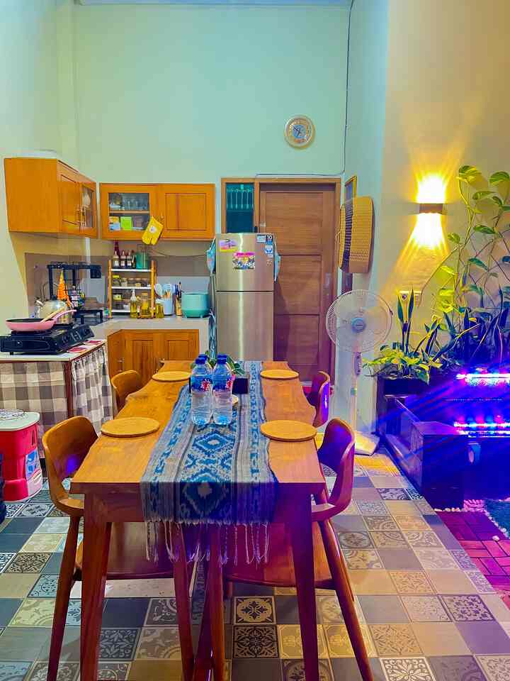 Natural wood tone kitchen and dining room featuring wooden table, chairs, wall sconce with cozy ambiance