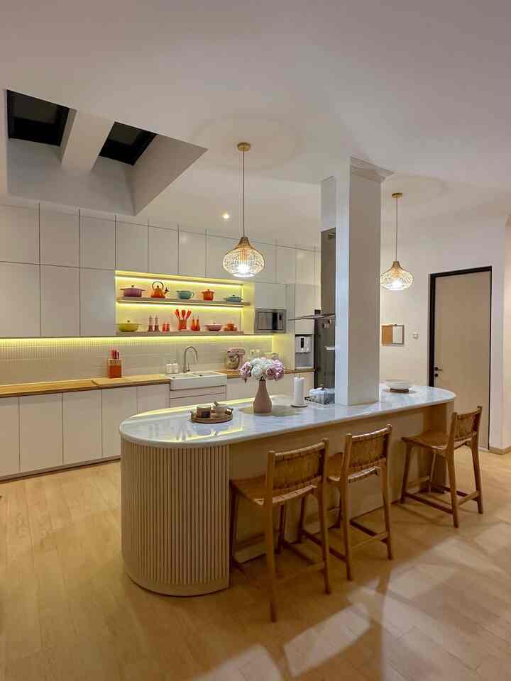 Modern kitchen combining white and wood tones, featuring a marble island and pendant lights in a cozy atmosphere