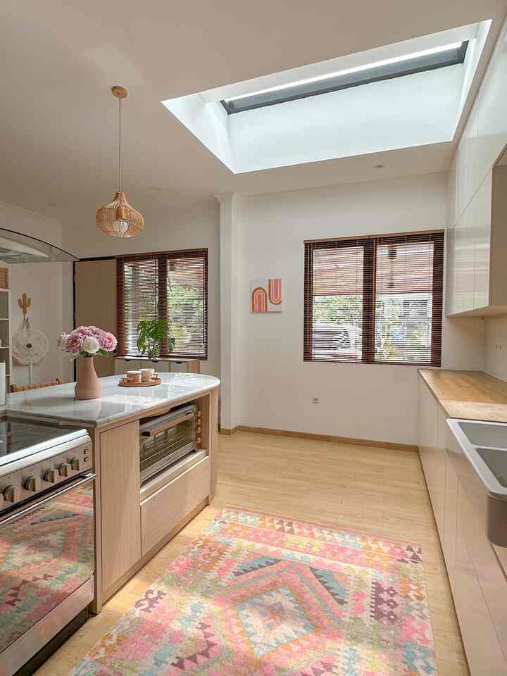Bright white-walled kitchen featuring natural wood tones, a bohemian carpet, and rattan pendant lighting creating a cozy atmosphere