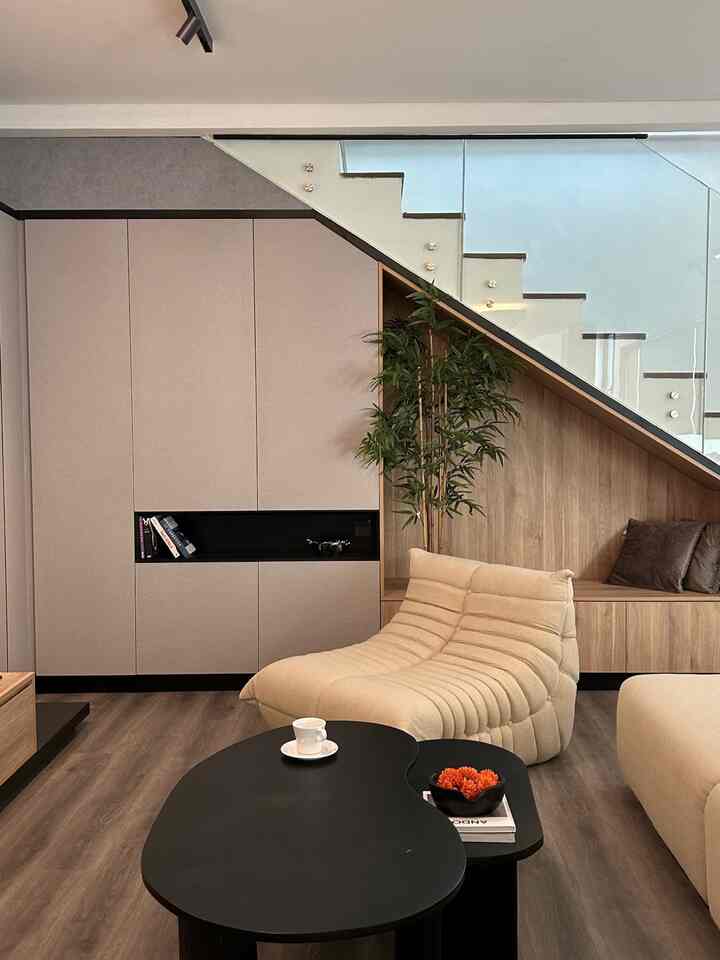 Natural color toned living room with low ceiling, featuring corner storage cabinetry and beige sofa for a cozy atmosphere