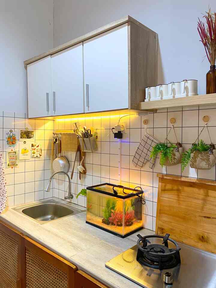 Ini adalah cerita renovasi dapurku ✨

Berawal dari rumah standar, tidak ada yg spesial dari dapur ini. Denahnya sudah sesuai dengan developer. Kami hanya merubah keramik backsplash dan tablenya. 

Untuk pintu, kami sesuaikan dengan tema meja makan yg terbuat dari kayu jati dengan variasi rotan, sehingga menjadi senada. Kami menggunakan jasa tukang kayu terdekat, yg mana rotan gulungan dibeli di marketplace.

Keramik yg telah kami buat ternyata tingginya kurang, sehingga minyak terciprat di tembok. Sudah mencoba cat anti minyak tetapi masih ada bekas noda, sehingga stiker kotak kotak menjadi pilihan praktis untuk menutup kekurangan tersebut.

Jadi, itulah sedikit cerita dari dapur sederhana kami #kitchenset #stikerdapur #dapursegaris #dapurkecil #sinkdapur #komportanam #tanamangantung #mydreamkitchen #kitchenrenovation #kitchenstyling