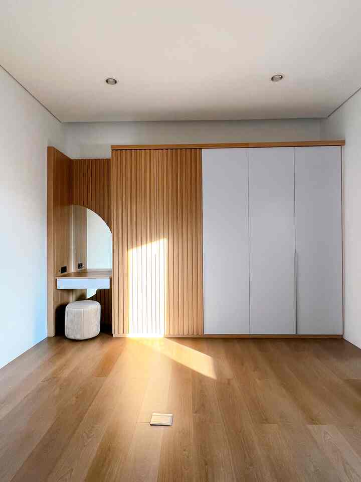 Natural wood tone and white bedroom featuring built-in closet and vanity desk along the wall with a simple, clean atmosphere