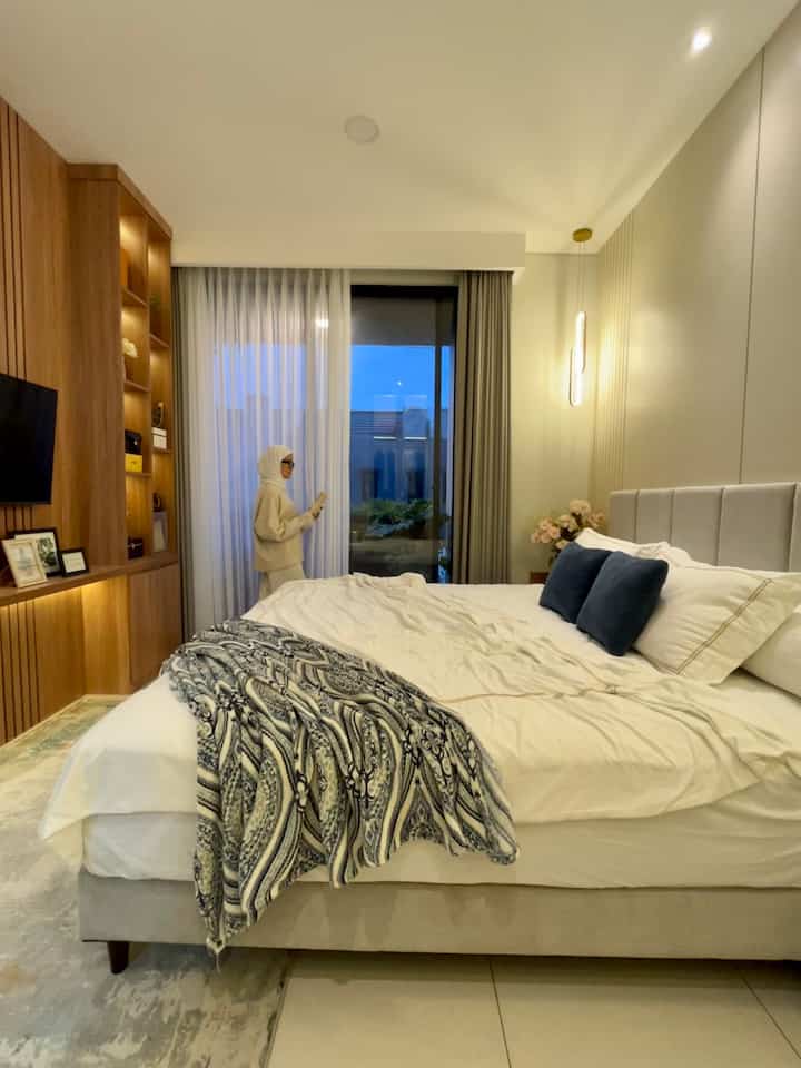 White and beige toned bedroom featuring a large bed and pendant light, creating a cozy modern interior