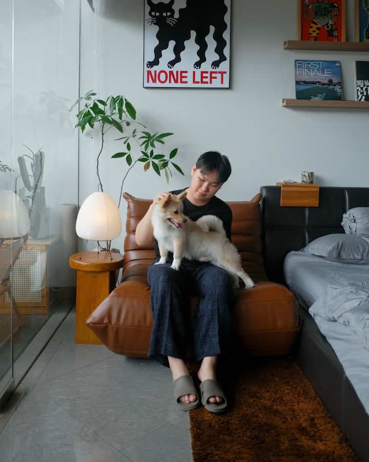 Cozy living room corner with warm brown tones and natural materials, featuring a man sitting with his dog on a Togo sofa