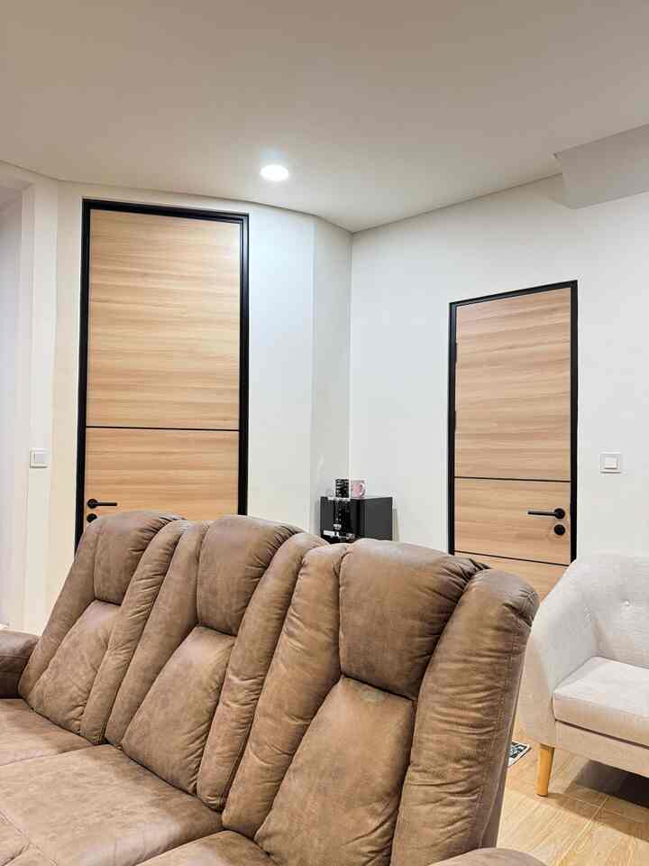 Living room with brown recliner sofa and wood tone doors against white walls