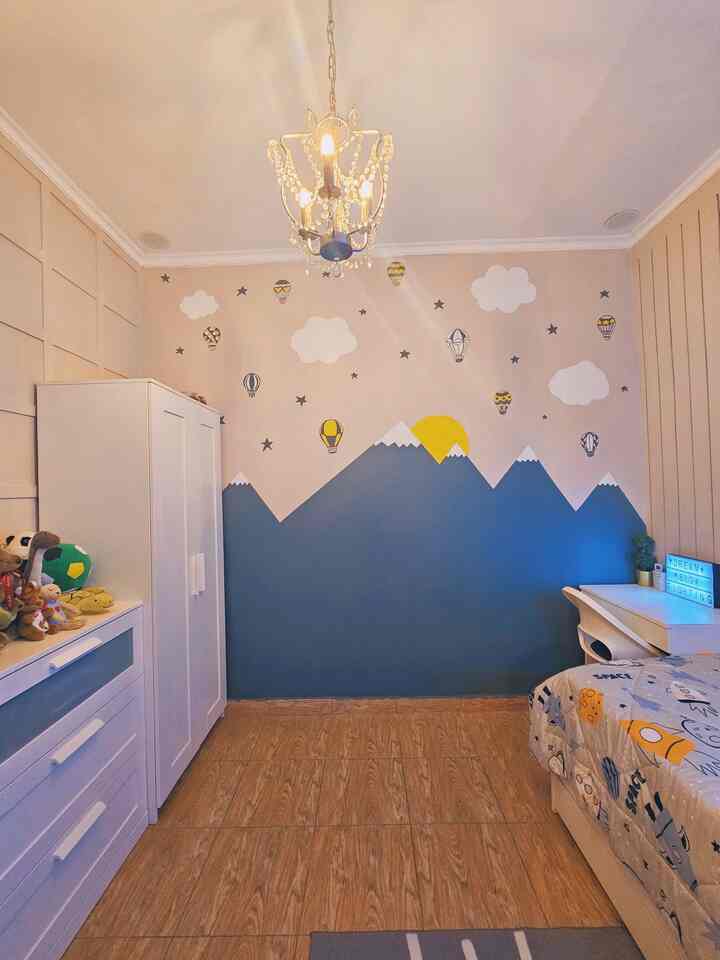 Beige and blue toned kids' room featuring a mountain and hot air balloon wall mural with white furniture creating a cozy atmosphere