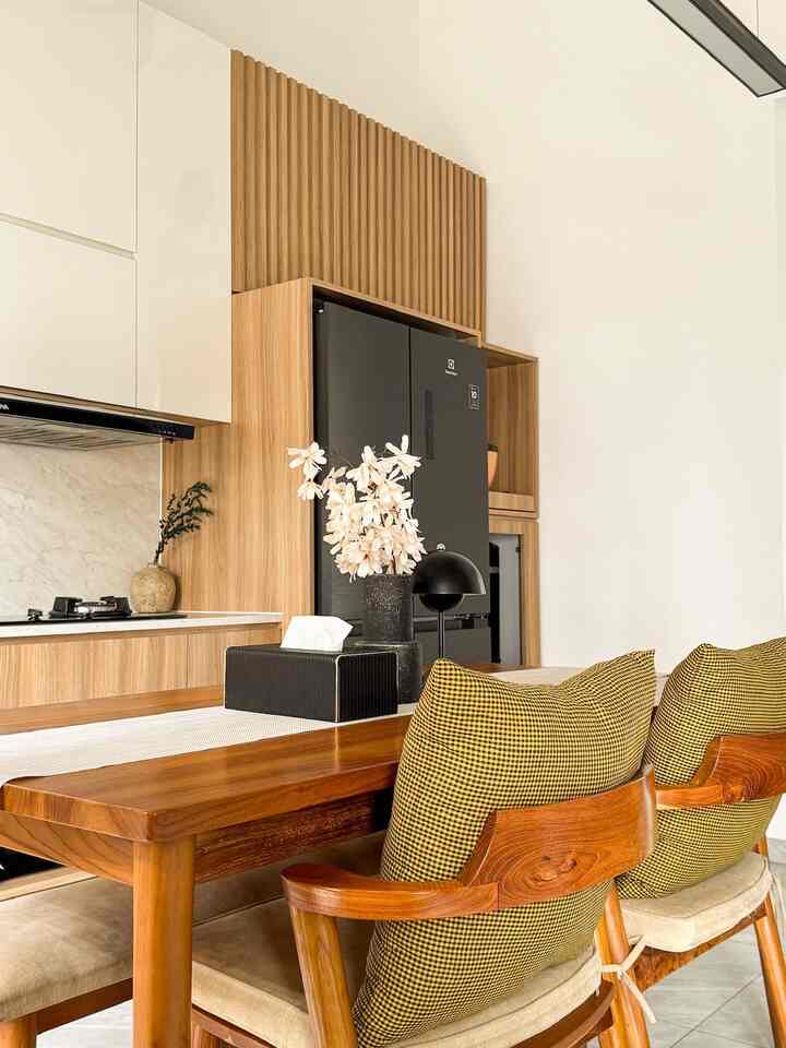Natural wood tones and black accents in a kitchen and dining area featuring a vase on the table, creating a cozy cafe style interior