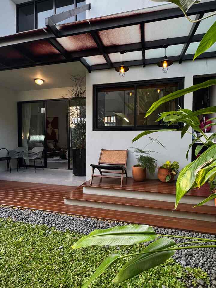 Wood tone and white balcony terrace featuring an armchair and plants in a modern outdoor space