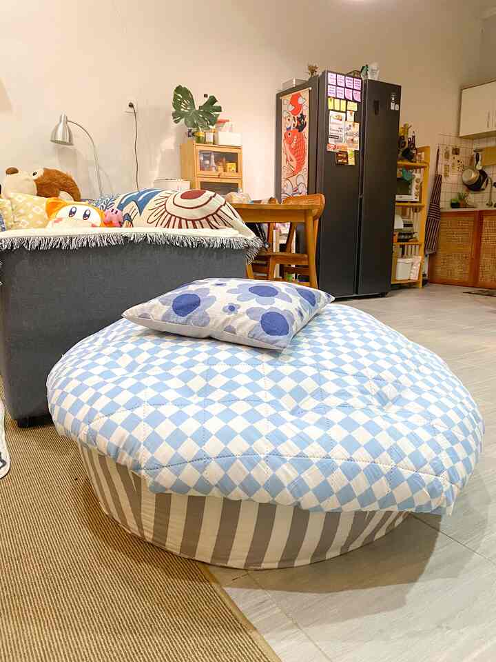 Bright blue and beige toned living room featuring a bean bag, sofa, dining table, and kitchen furniture with a natural cozy atmosphere