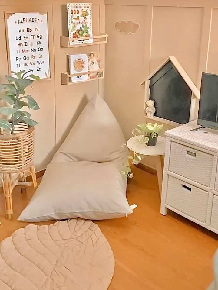 Beige-toned kids' room featuring a bean bag, carpet, and plants with a cozy atmosphere