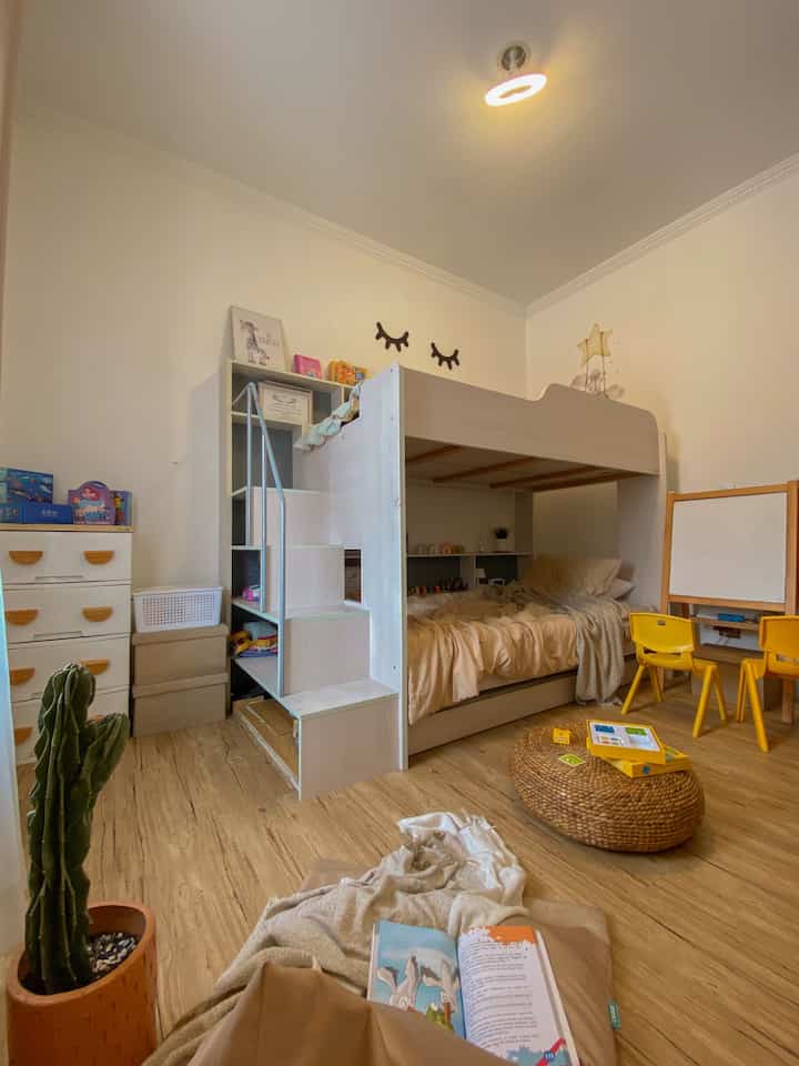 Light brown floor and white walled kids' room featuring multifunctional bunk bed and cozy reading area