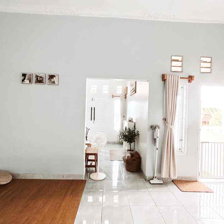 Bright white and brown toned living and entrance area featuring curtains and standing fan with a clean, welcoming atmosphere