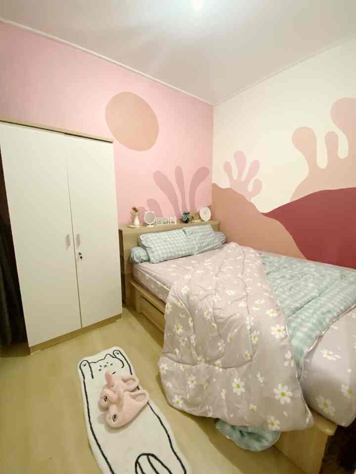 Pastel pink toned bedroom featuring floral bedding and a wardrobe, creating a cozy atmosphere