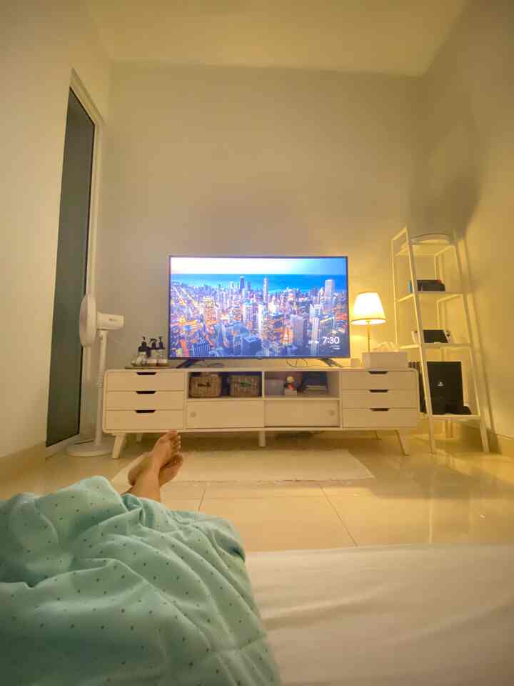 White-toned living room space featuring a TV stand and floor lamp with a simple, clean interior ambiance