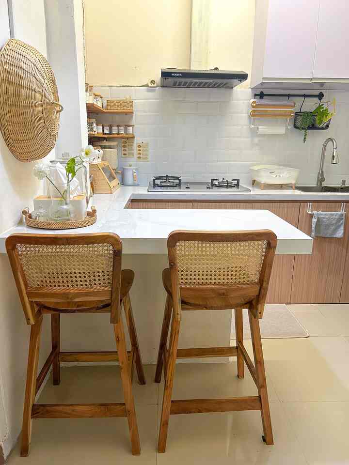 Beige and wood-toned small kitchen for two, featuring rattan bar stools and clean white countertops creating a warm atmosphere