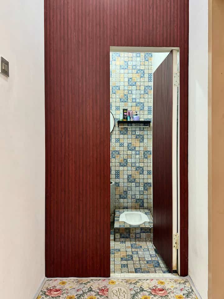 Blue and brown toned bathroom featuring patterned ceramic tiles and a squat toilet, creating a cozy atmosphere
