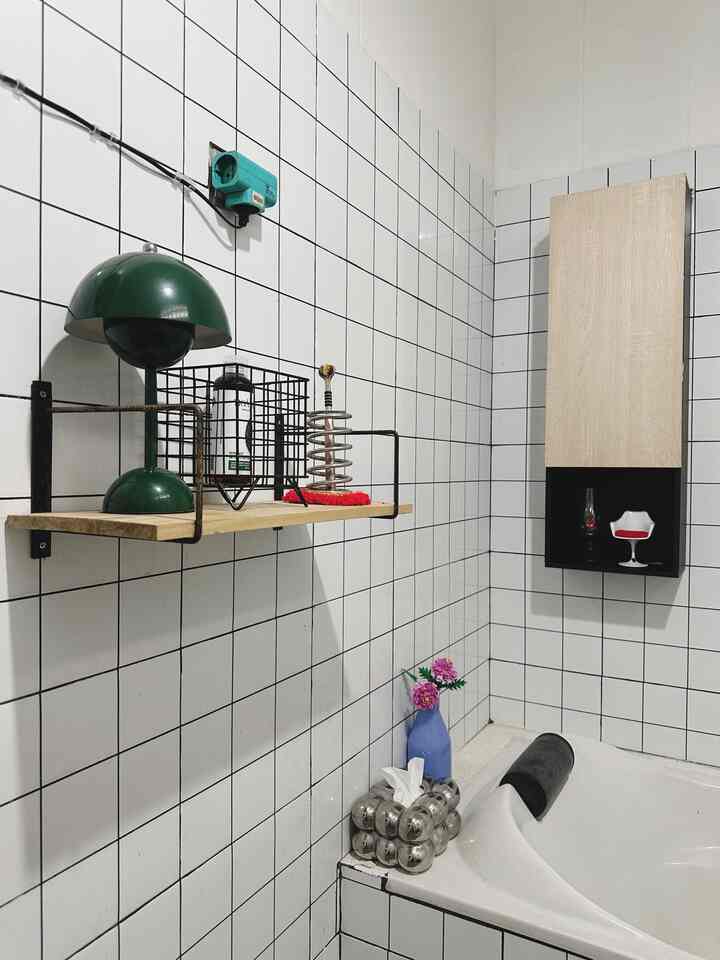Clean bathroom space with white tiled walls, wooden shelf, and bathtub featuring a minimalistic design