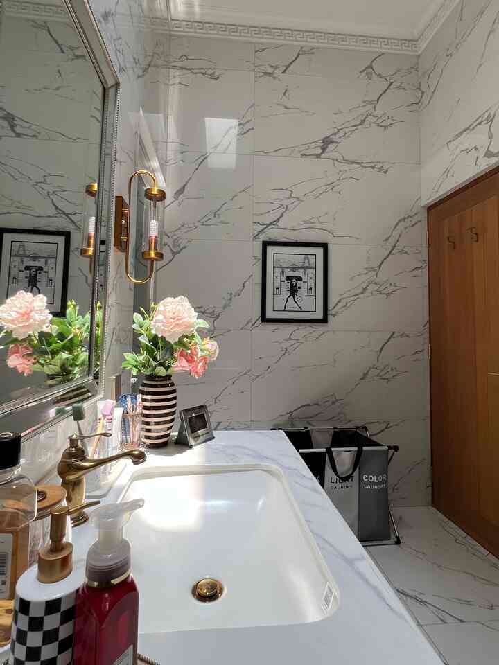 White bathroom with marble pattern featuring wash basin and gold-accented faucet in a clean design