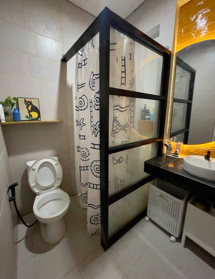 Renovasi Low budget Sharing Bathroom 🚿
Kamar mandi ini letaknya di lantai 2. Yg merupakan material bawaan dr developer adalah shower, floordrain, keramik lantai, dinding, toilet, keramik meja wastafel beton.

Make Over yg dilakukan:
✨Memberikan batas area kering dan area basah (shower) dengan aluminium kaca dan tirai waterproof.
✨Dekorasi keramik backsplash di area wastafel dgn Tile warna kuning honey teak agar terkesan lebih fresh.
✨Cermin setengah bulat dgn Led strip seperti halfmoon agar lebih estetik.
✨Rak motif kayu untuk penempatan toiletries.
✨Menambah niche di area shower pada jendela untuk penempatan sabun & shampoo
✨Ambalan dinding motif terazo kuning yg terbuat dari recycled plastic tebal yg waterproof di atas toilet untuk meletakkan pajangan dan difusser.
✨Kabinet wastafel sbg penyimpanan alat kebersihan dan keranjang laundry beroda yg sangat praktis untuk tempat baju kotor.

Semoga bermanfaat menjadi ide dekorasi kamar mandi yg low budget ya teman-teman 🛀

#RenovasiKamarMandi #BathroomMakeOver #InspirasiKamarMandi #DekorasiKamarMandi #TiraiKamarMandi #TiraiWaterproof #KabinetWastafel #HiasanFlush #CerminKamarMandi #TilesBathroom #keramikkamarmandi #AmbalanEstetik 