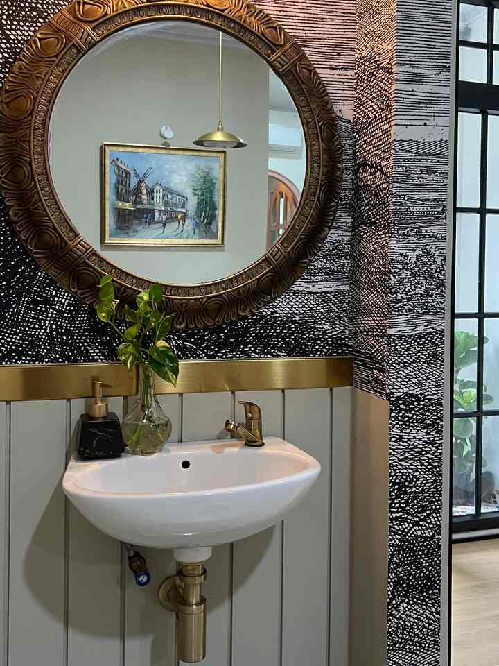 Bathroom space featuring a gold ornate round mirror and white ceramic sink with gold faucet, luxurious interior vibe