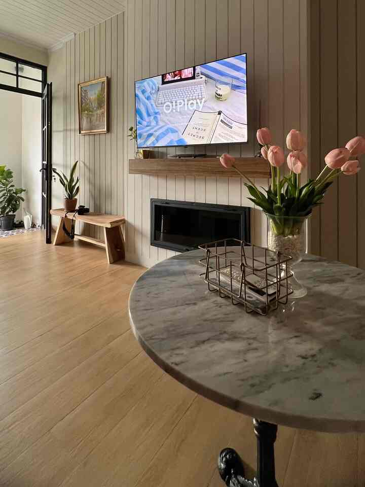 White and wood tone living room featuring a marble table with a vase, creating a soft and cozy atmosphere