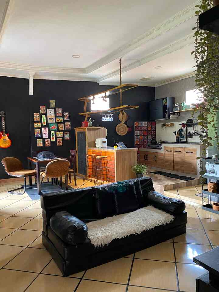 Black and brown toned open space living room with kitchen and dining area, featuring industrial style elements