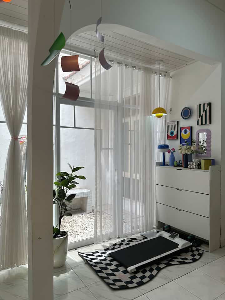 Bright and airy white-toned space featuring sliding door with curtains, treadmill, and storage cabinet for hobby exercise
