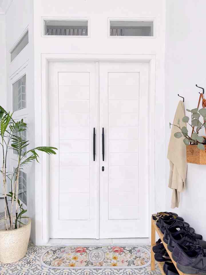 Bright entrance in white and beige tones featuring a neat shoe rack and green plant with a cozy, clean atmosphere