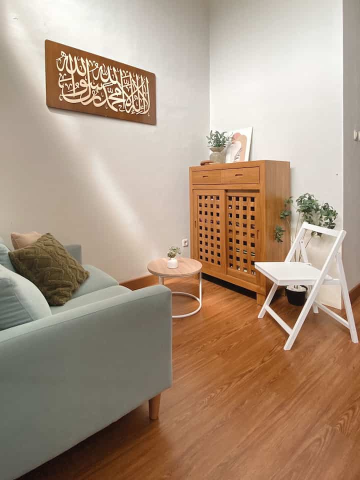 Small simple living room with white walls, wood tone floor, sofa, and round coffee table arranged neatly