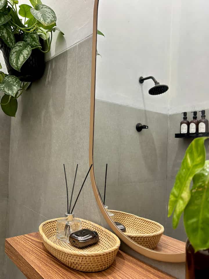 Natural color and wood tone bathroom featuring a mirror, diffuser, and plants creating a cozy atmosphere