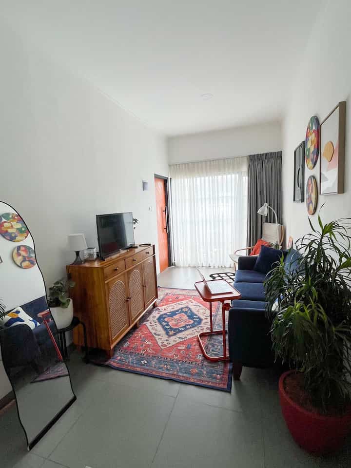 Small living room featuring navy sofa and red carpet, complemented by natural light and plants in a simple modern style