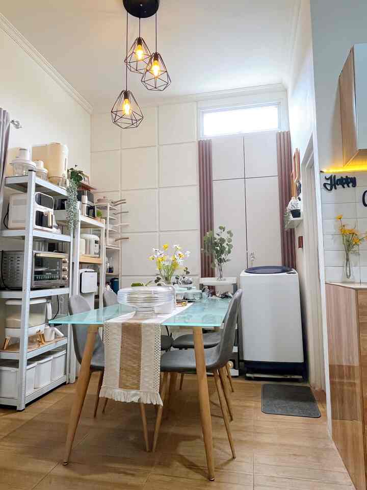 White-walled kitchen-dining space with brown flooring, featuring a glass dining table and gray chairs in a cozy setting