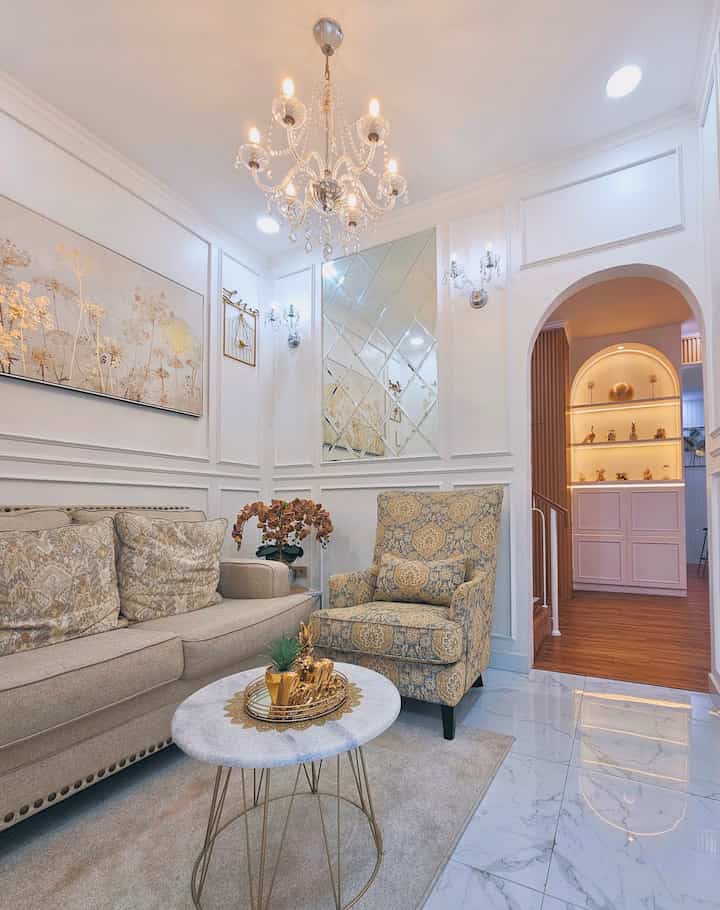 Classic style living room in white and gold tones featuring beige sofa and patterned armchair with elegant ambiance