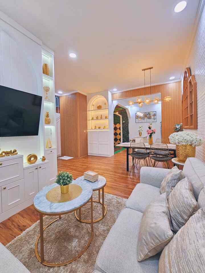 Open space living and dining room with white and wood tones, modern and warm atmosphere featuring sofa, dining table, and pendant lights