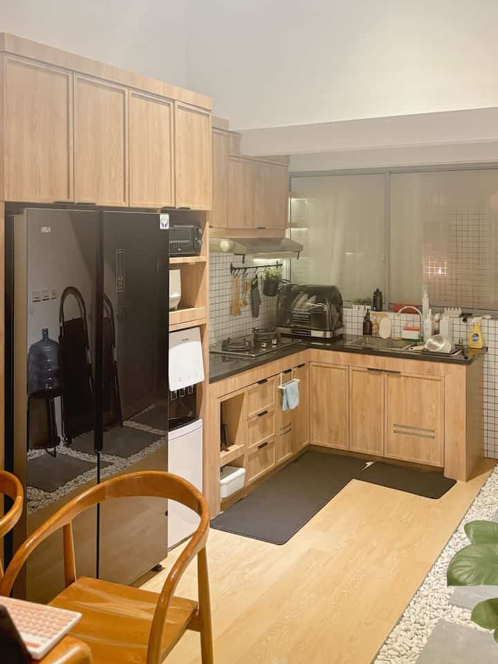 Natural wood tone and black refrigerator define compact 4.5-tatami L-shaped kitchen space with cozy atmosphere