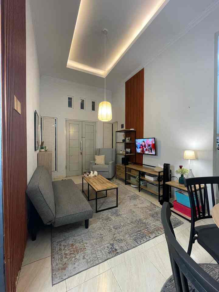 White walls and gray sofa bed in a wood-tone industrial style living room, with a rug and pendant light creating a cozy atmosphere